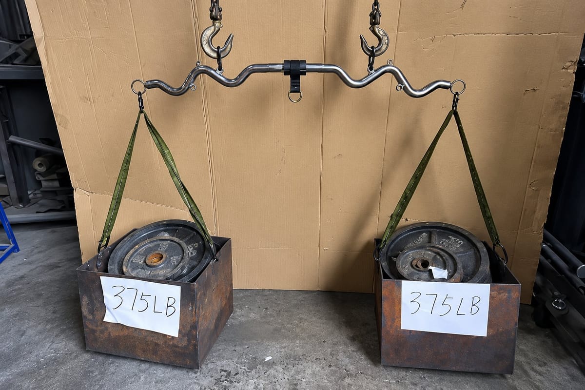 The Bodylastics Resistance Bands Bar hanging from two hooks with a 375 lb load at each end, 750 lbs in total.