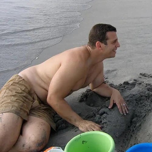 Blake in the 2000s, out of shape, building a sandcastle at the beach.