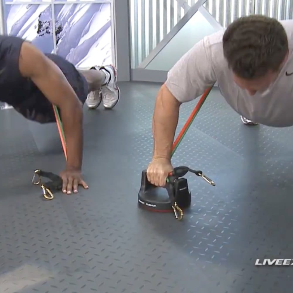 A man does push-ups holding Bodylastics push-up handles, with a band running from each handle.