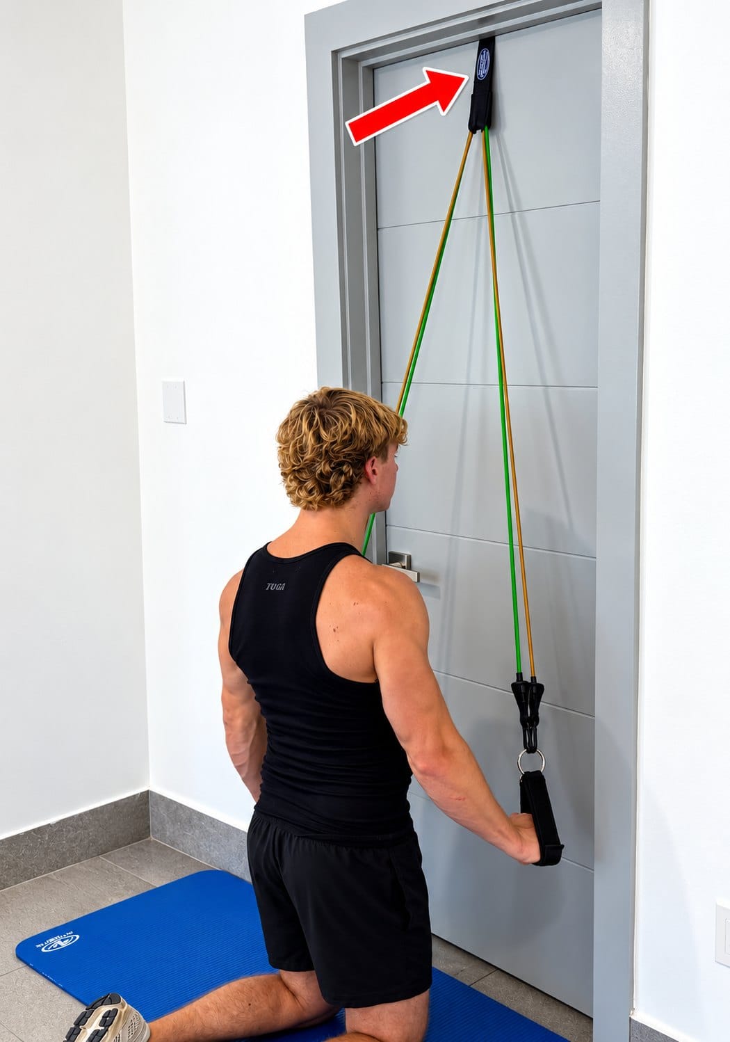 A man kneels facing a door and pulls a Bodylastics band down from a door anchor fixed at the top of the door.